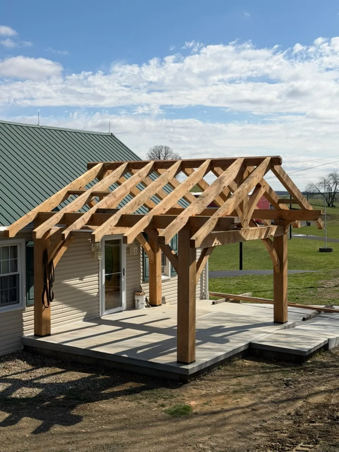 Angled view of the hemlock timber-frame patio structure showing posts, beams and braces.