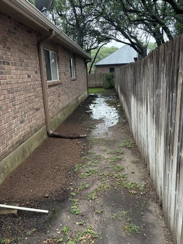 Standing water in a flat side yard beside a house before the drainage work.